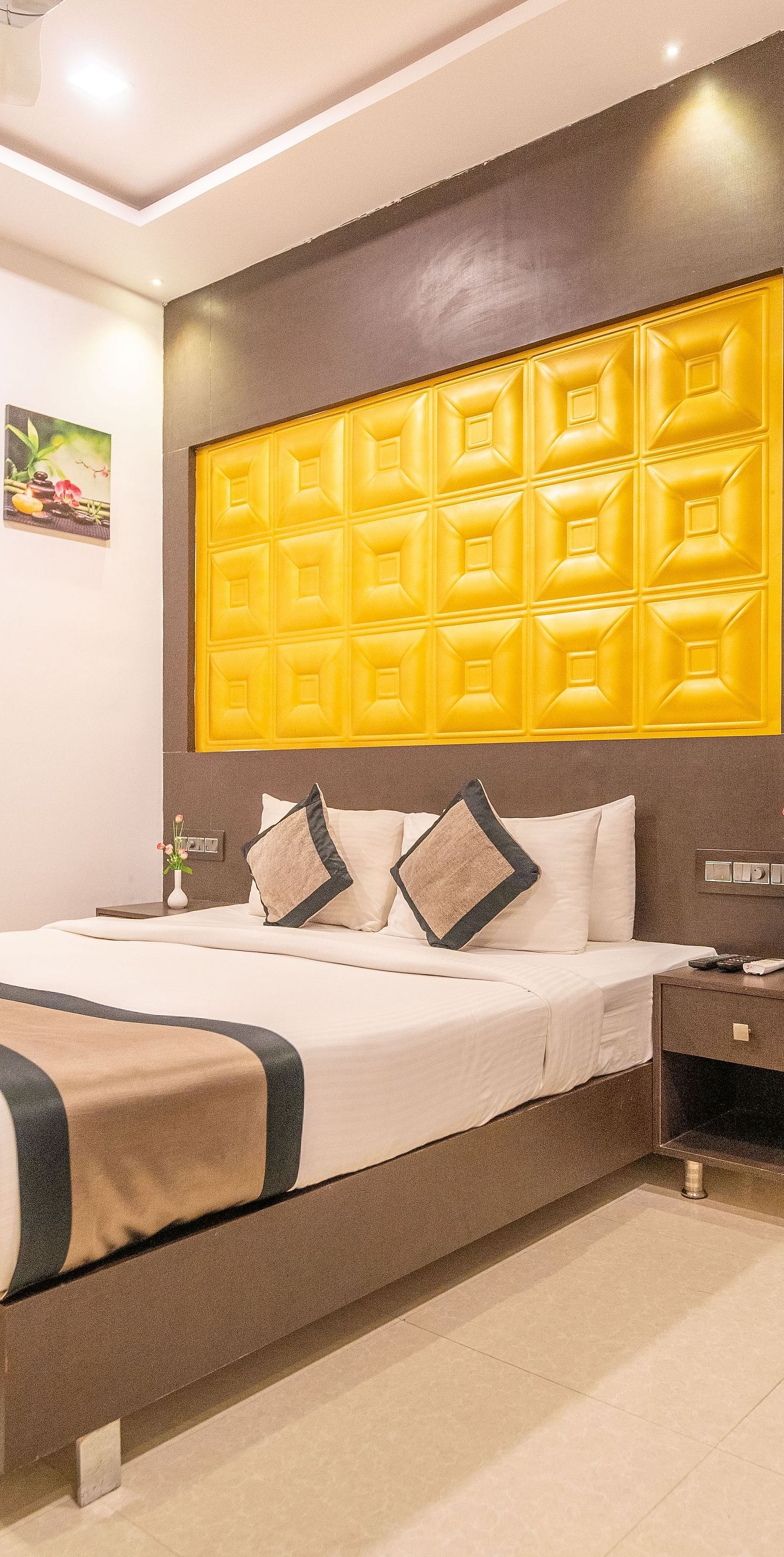 A room with a bed and three flower prints on the side at Parampara Residency, Kushalnagar.