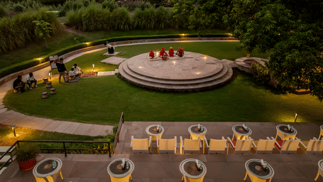 Aerial view of a landscaped garden featuring a circular outdoor seating area, pathways and lush greenery.