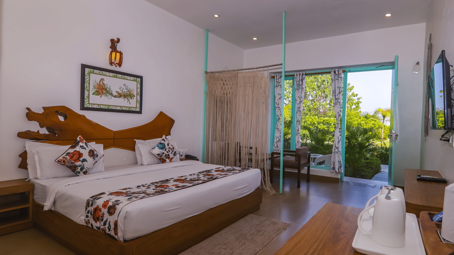 Spacious bedroom at Vedikant Resorts The Mallard Corbett with two beds, open curtains, and outdoor greenery visible through the sliding glass door.