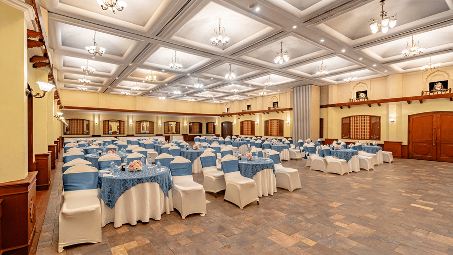 Corner view of the expansive Emperor Hall at Noor-Us-Sabah Palace, Bhopal, with a flower bouquet placed in the centre of each table that is cover with a patterned blue coloured-table cloth.