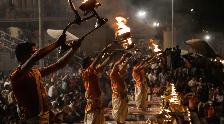 Priests performing the evening 'Ganga Aarti' ceremony with large flaming lamps on the banks of a river.