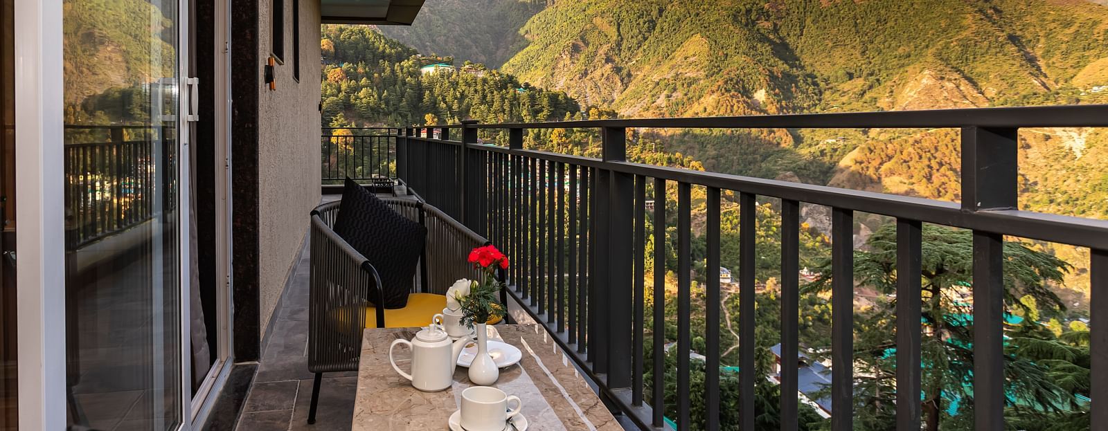 An image of a balcony attached to a Suite which has chairs and table overlooking the mountains - The Belvedere Himalayan Retreat, McLeodganj