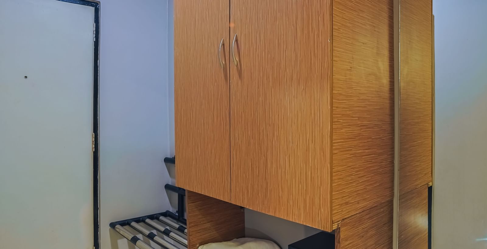 Wooden wardrobe with storage shelves and mini fridge at Max Hotel Prayagraj.