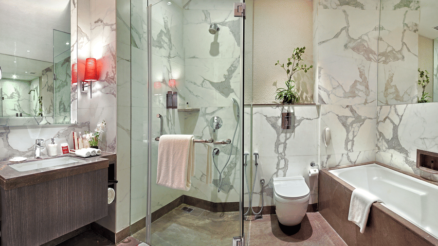 Suite bathroom at The Sonnet, Kolkata with a glass enclosed shower, bathtub, washbasin and toilet.