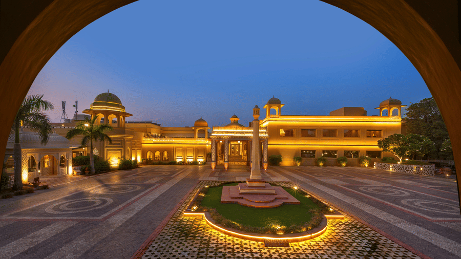 An overview of the facade of Heritage Village Resorts and Spa near Delhi in Manesar, with a large courtyard during twilight