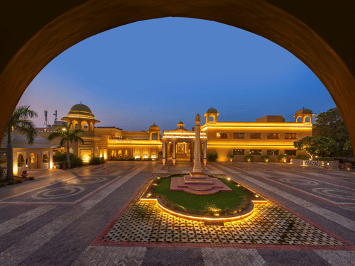 An overview of the facade of Heritage Village Resorts and Spa near Delhi in Manesar, with a large courtyard during twilight