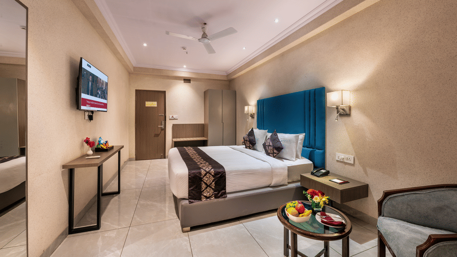 Lords Eco Inn bedroom with a large bed, a headboard, a ceiling fan, and simple wooden furniture.