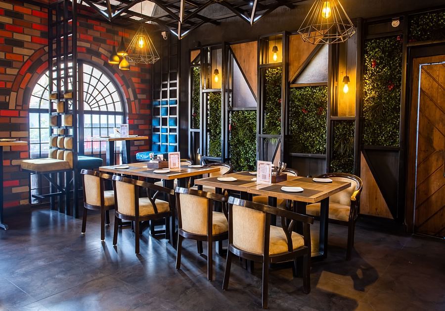 Elegant indoor restaurant seating with a wooden table and four chairs on each side - The Wedlock Greens Hotel & Resort, Dhanbad