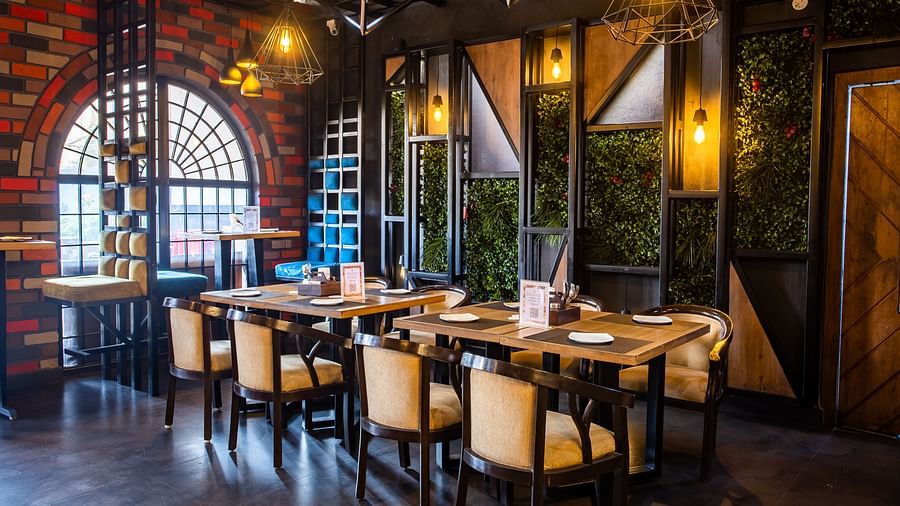 Elegant indoor restaurant seating with a wooden table and four chairs on each side - The Wedlock Greens Hotel & Resort, Dhanbad
