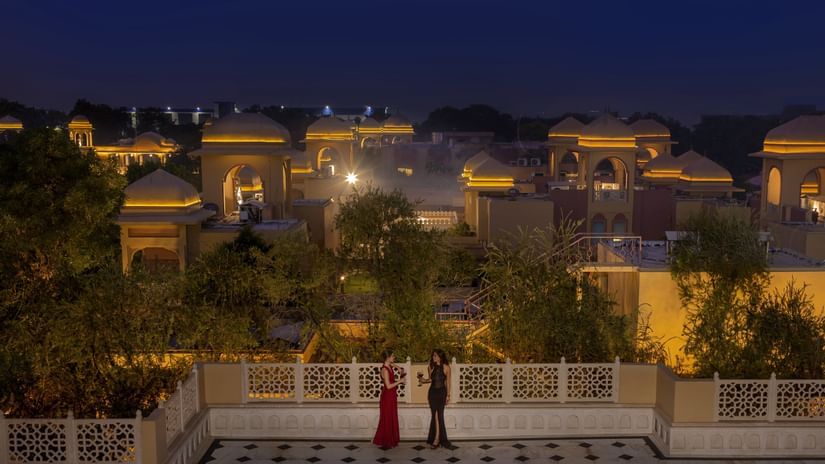 Evening view from a terrace overlooking the property buildings at Heritage Village Resorts & Spa, Manesar, with warm lights
