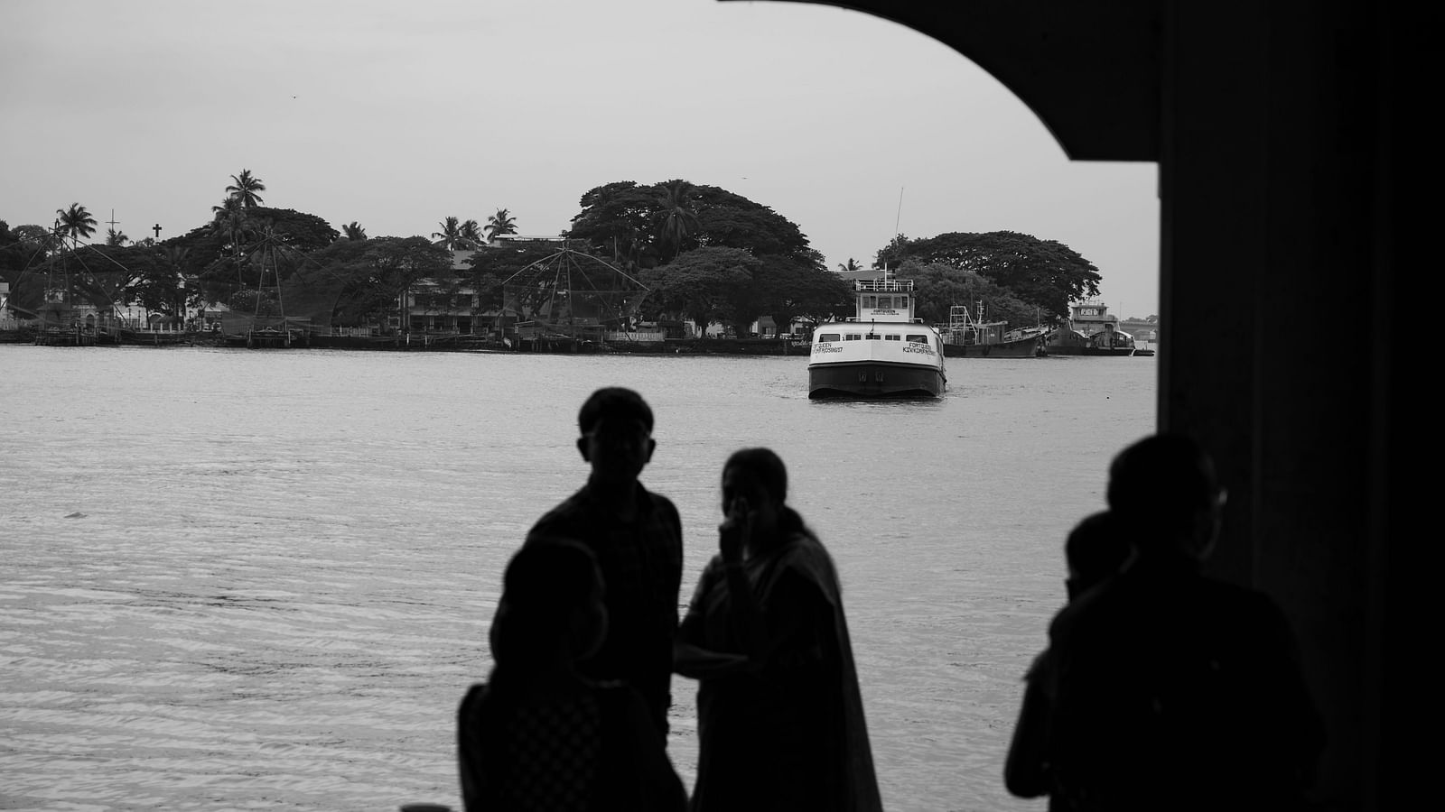 an image of silhouettes of a people standing near fort kochi during the day