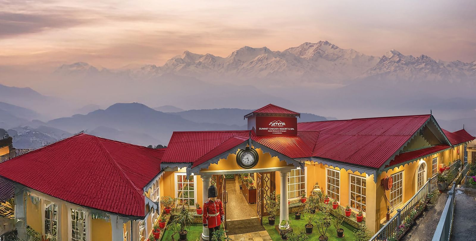 Aerial facade view of Summit Oakden Resort & Spa, Mall Road, with a sunset-lit cloudy sky and majestic mountains in the background
