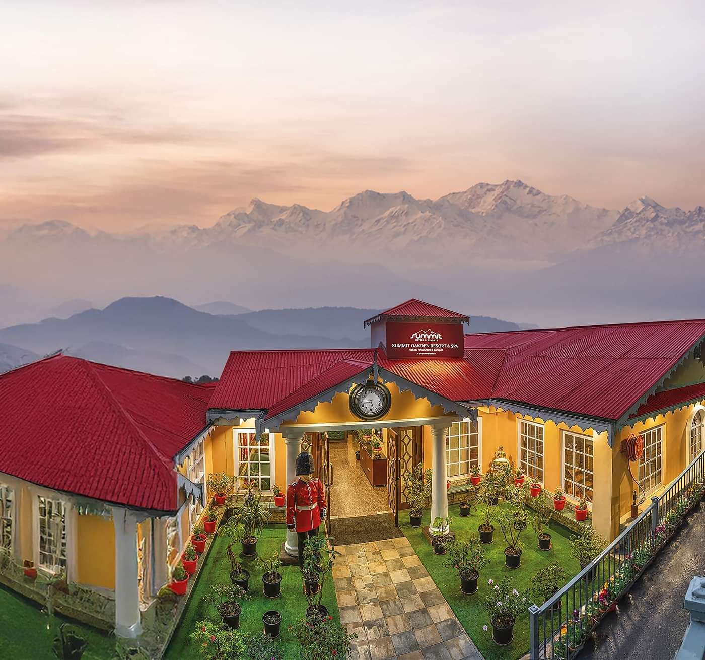 Aerial facade view of Summit Oakden Resort & Spa, Mall Road, with a sunset-lit cloudy sky and majestic mountains in the background