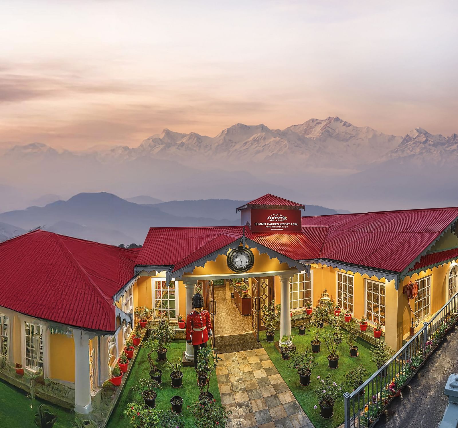 Aerial facade view of Summit Oakden Resort & Spa, Mall Road, with a sunset-lit cloudy sky and majestic mountains in the background