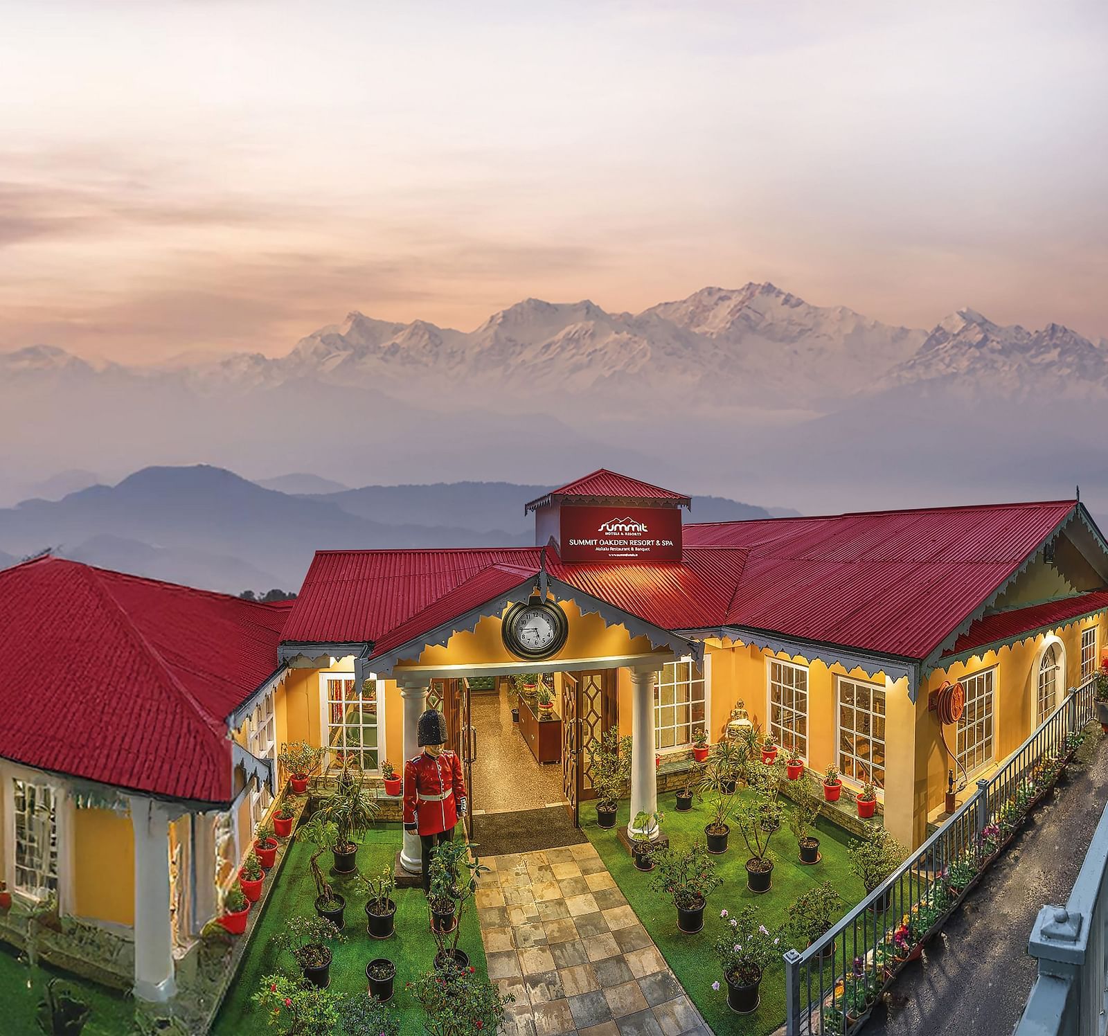 Aerial facade view of Summit Oakden Resort & Spa, Mall Road, with a sunset-lit cloudy sky and majestic mountains in the background