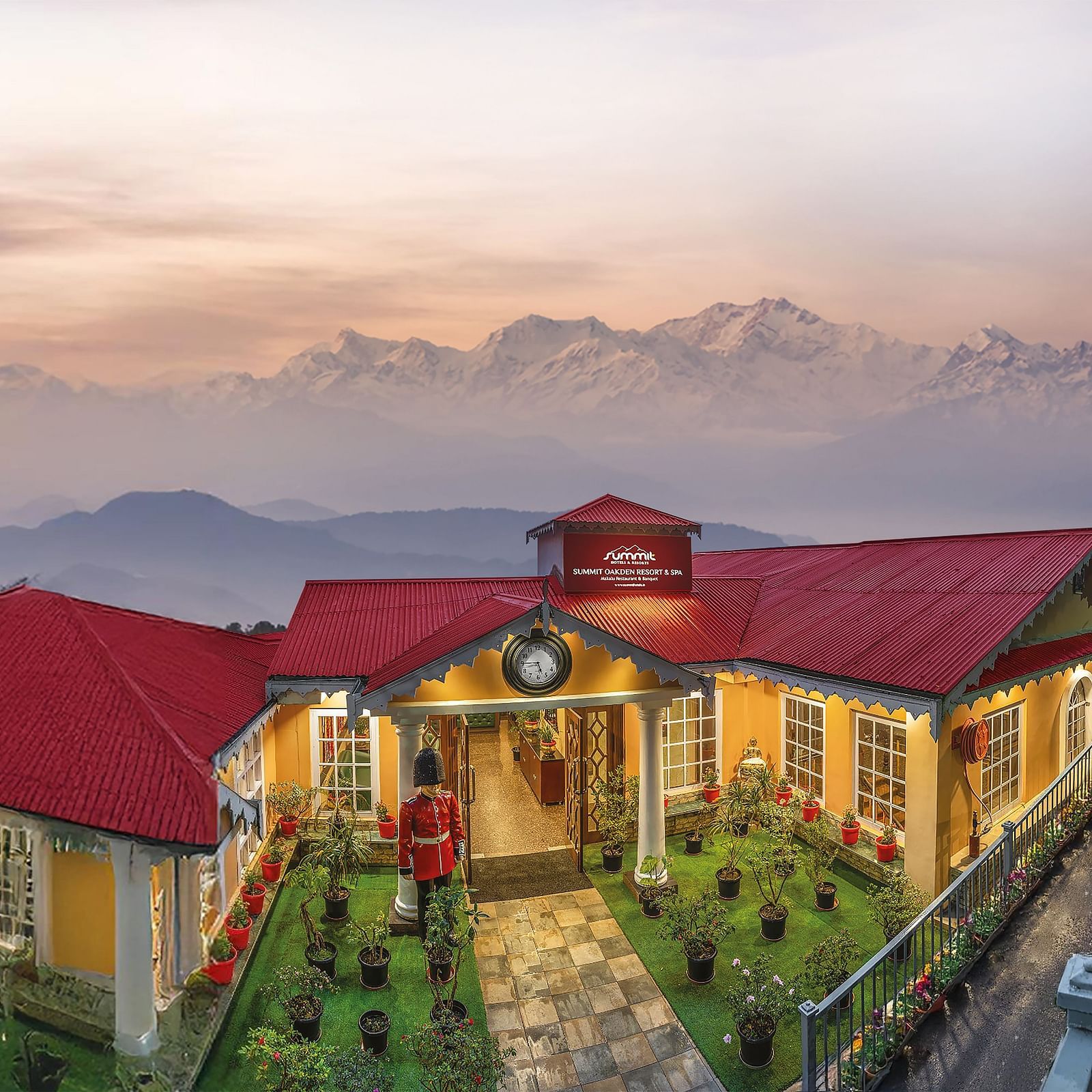 Aerial facade view of Summit Oakden Resort & Spa, Mall Road, with a sunset-lit cloudy sky and majestic mountains in the background