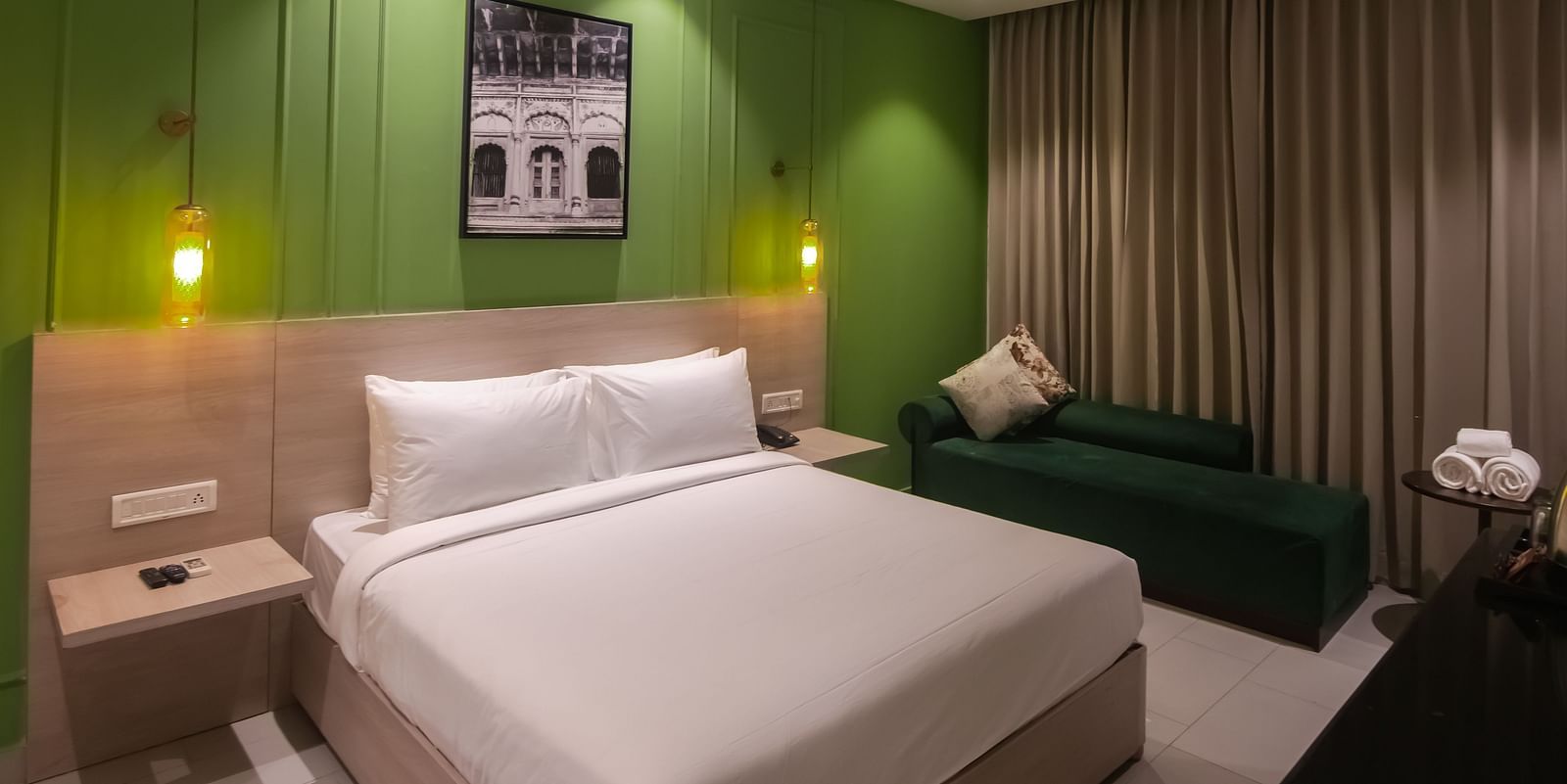 Deluxe Rooms at Wonder Hills Hotel with a king sized bed, bedside lamps, and a cosy corner sofa for added comfort
