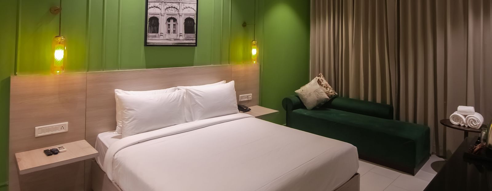 Deluxe Rooms at Wonder Hills Hotel with a king sized bed, bedside lamps, and a cosy corner sofa for added comfort