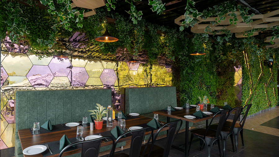 Tables and chairs placed in a dining space that is decorated with leaves and lights | Voyage The Royal Retreat 