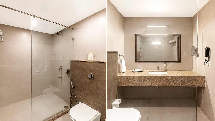A  split bathroom view, showcasing a glass-door shower on one side and a sink with a large mirror on the other - Via Lakhela Resort & Spa, Kumbhalgarh