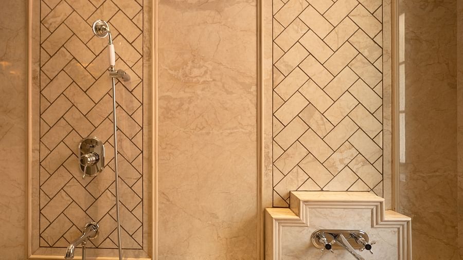 Luxurious beige marble shower area with chrome fixtures, featuring an elegant herringbone tile pattern on recessed wall panels - Panna Vilas Palace