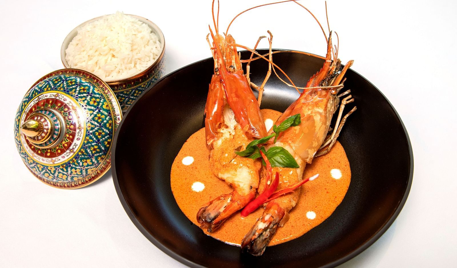 Thai-style prawn curry with jasmine rice, elegantly served in a black bowl with a traditional decorative lid