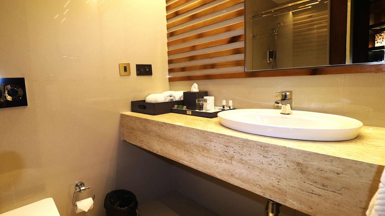 A modern bathroom at Swosti Premium, Bhubaneswar, with a sink, mirror, and toiletries.