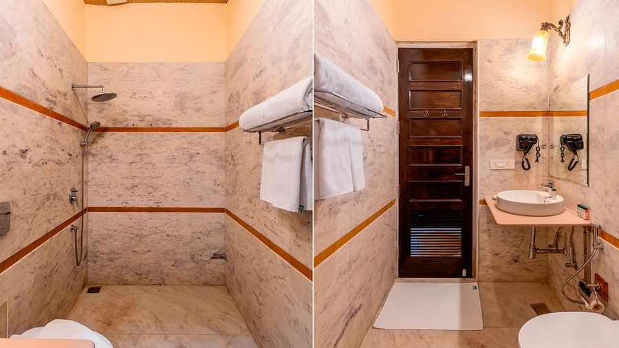 Modern bathroom with marble walls, walk-in shower, and twin mirrors at Kesar Bagh Palace.