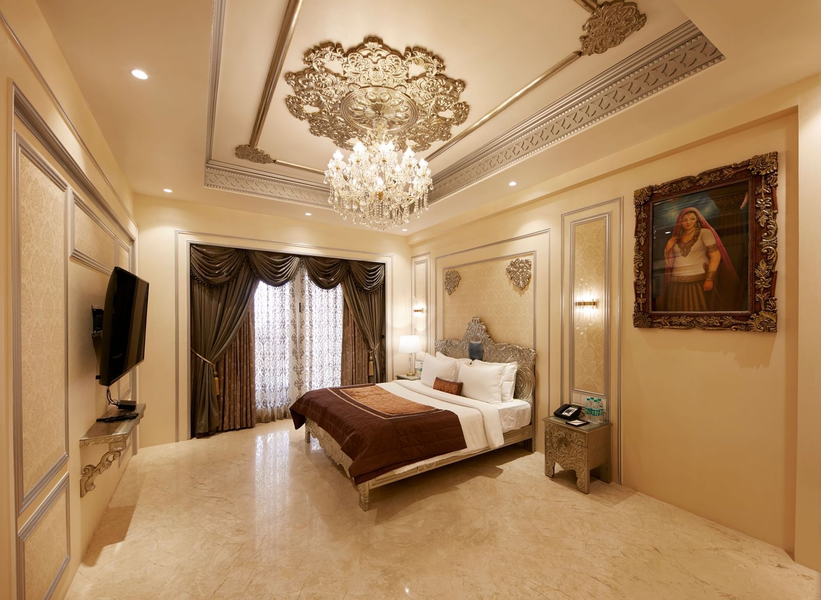 A luxurious bedroom in Mahabalipuram with a chandelier, beige tones, and a plush brown bedspread – Kaldan Samudra, one of the finest 5 Star Hotels in ECR