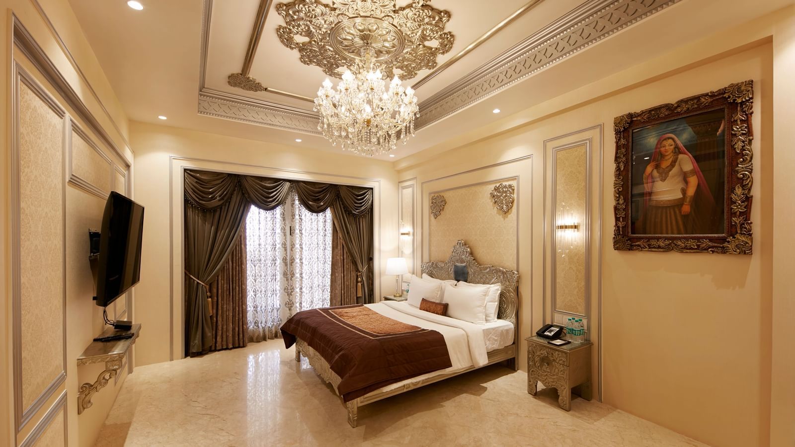 A luxurious bedroom in Mahabalipuram with a chandelier, beige tones, and a plush brown bedspread – Kaldan Samudra, one of the finest 5 Star Hotels in ECR