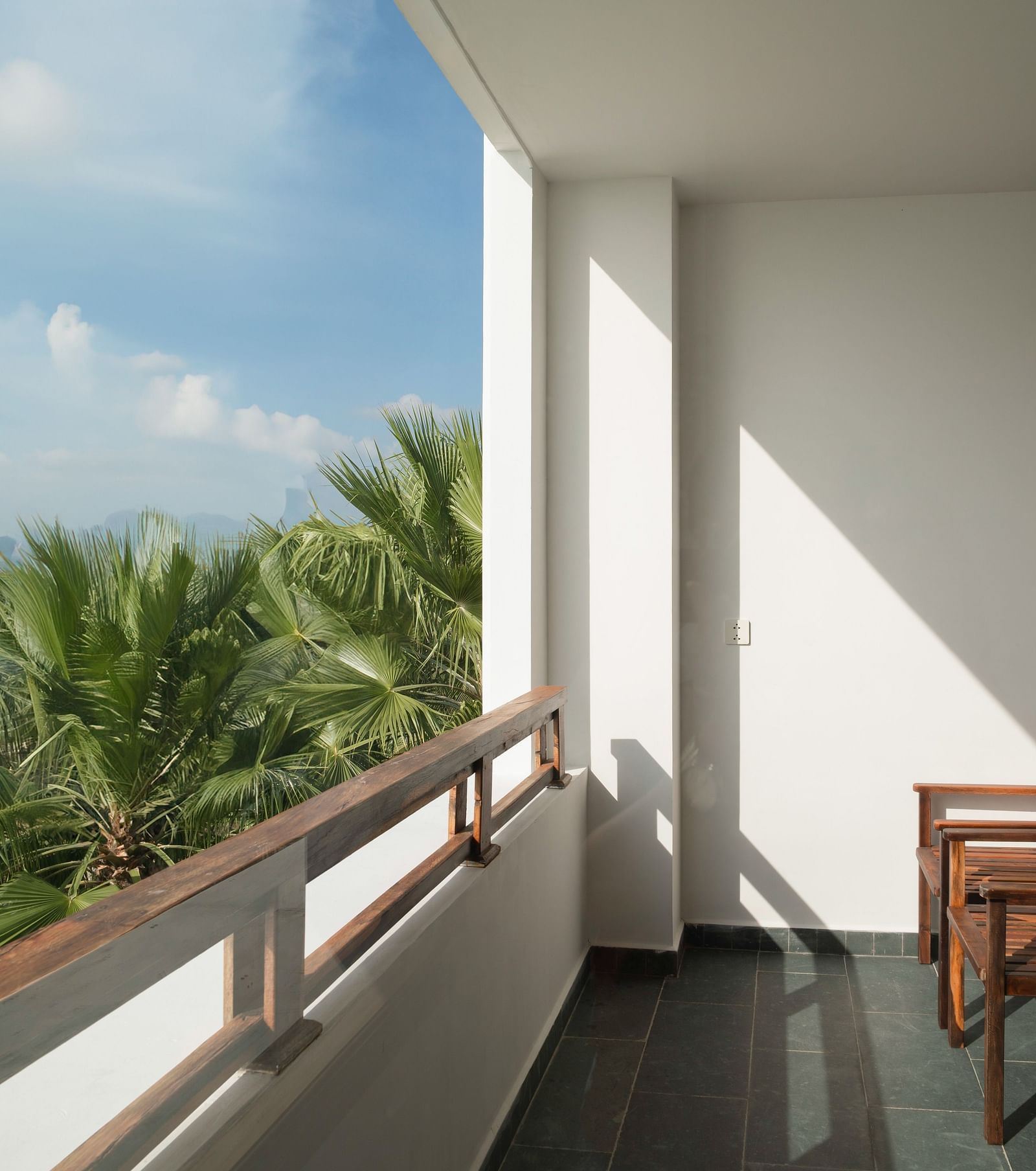 A balcony with comfortable wooden chairs for people to enjoy the sun light - Alibu Resort Nha Trang