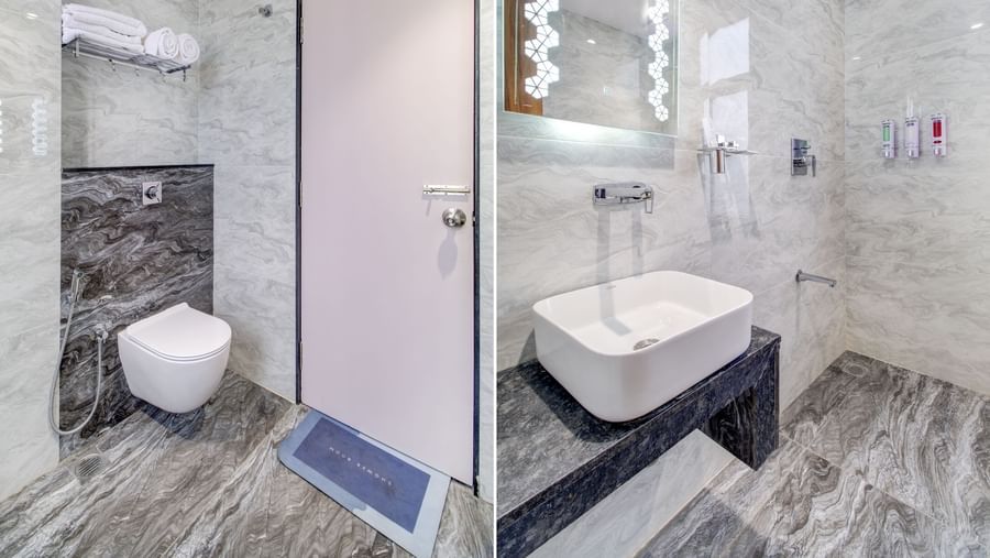 Modern bathroom with shower, wash basin, mirror, and water closet at Monday Hotels Amalapuram Heights