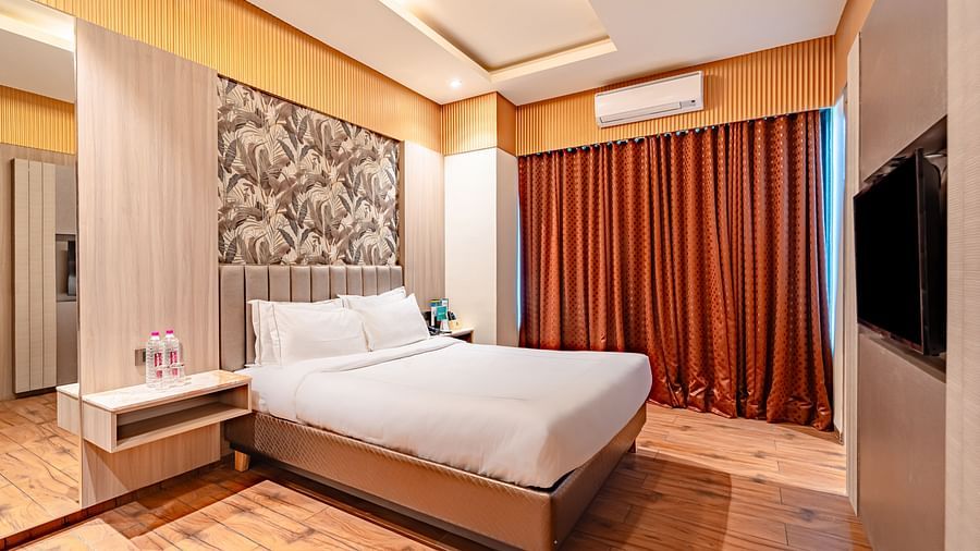 Family Room features a spacious bed, curtains covering the windows, and a wall-mounted television at Crescent Spa & Resort, Indore.