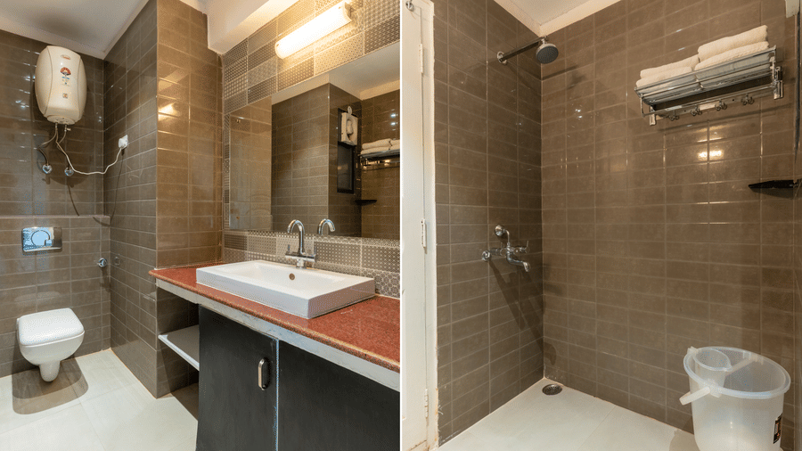 Interior view of a bathroom with grey wall tiles, a white sink, and a walk-in shower area at Himalayas Resort By The Lake Hill, Mukteshwar.