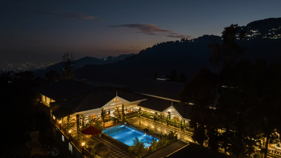Illuminated outdoor swimming pool glowing at night at Mayfair Manor, Jungpana.