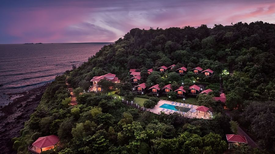 A resort nestled amidst rolling green hills seen during a sunset - Highland Sarovar Portico, Sindhudurg