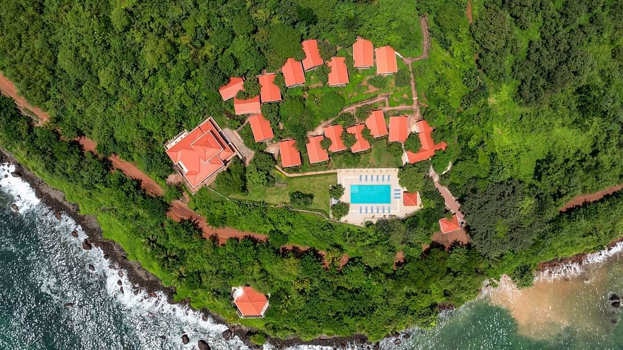 A breathtaking aerial view of Highland Sarovar Portico, Sindhudurg, nestled along a picturesque crescent-shaped coastline