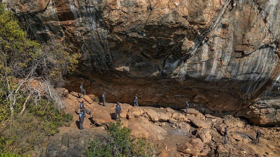 Visitors exploring Porivarai Cave under a large rock overhang with visible prehistoric wall art.