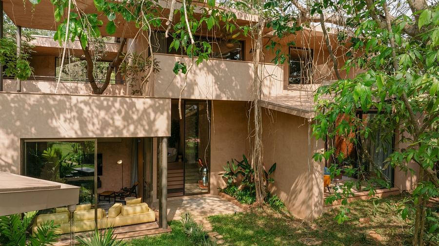 A modern, earthy exterior of Villa Moira by V Escapes, blending seamlessly with the surrounding vibrant green foliage.