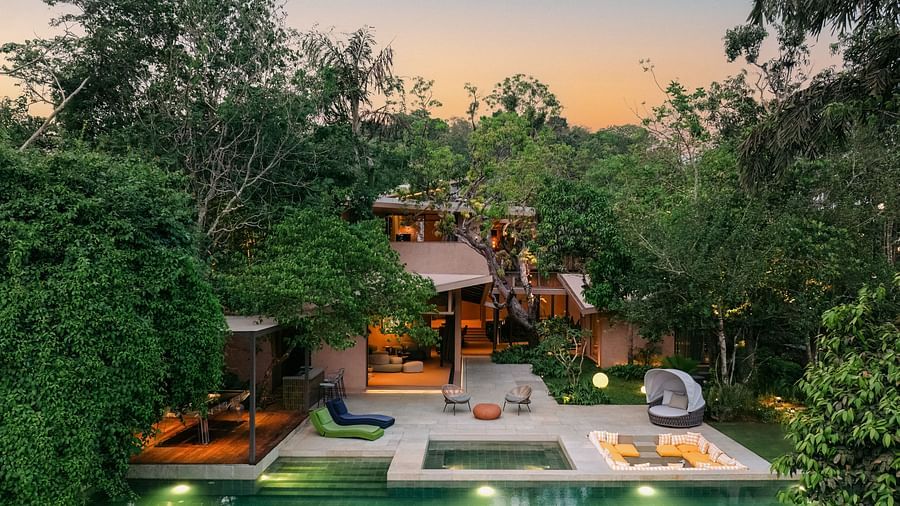 An evening view of Villa Moira by V Escapes, highlighting the illuminated swimming pool and outdoor lounge areas amidst the twilight glow.