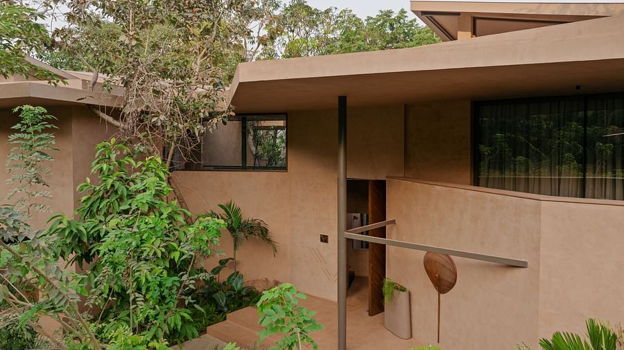 A detailed side view of Villa Moira by V Escapes, showcasing its multi-level, earthy-toned architecture nestled amongst the surrounding trees and vegetation.