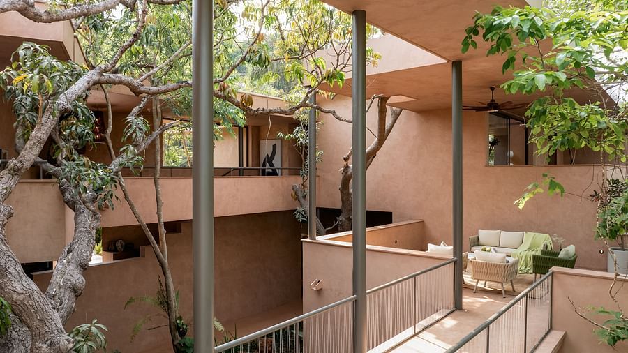 The multi-level, open-air terraced architecture of Villa Moira by V Escapes, featuring natural stone walls and intertwined tree branches providing shade.