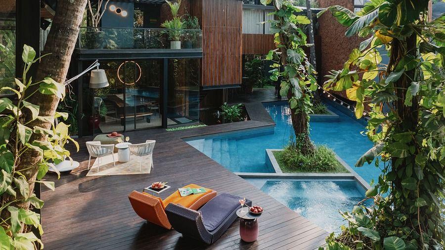 A swimming pool with colorful lounge chairs and lush greenery in the background.