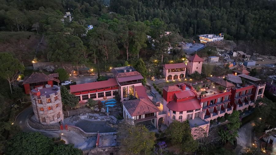 Aerial view of a mountain resort with red roofs, surrounded by dense greenery at twilight. | Mango Hill, Yercaud