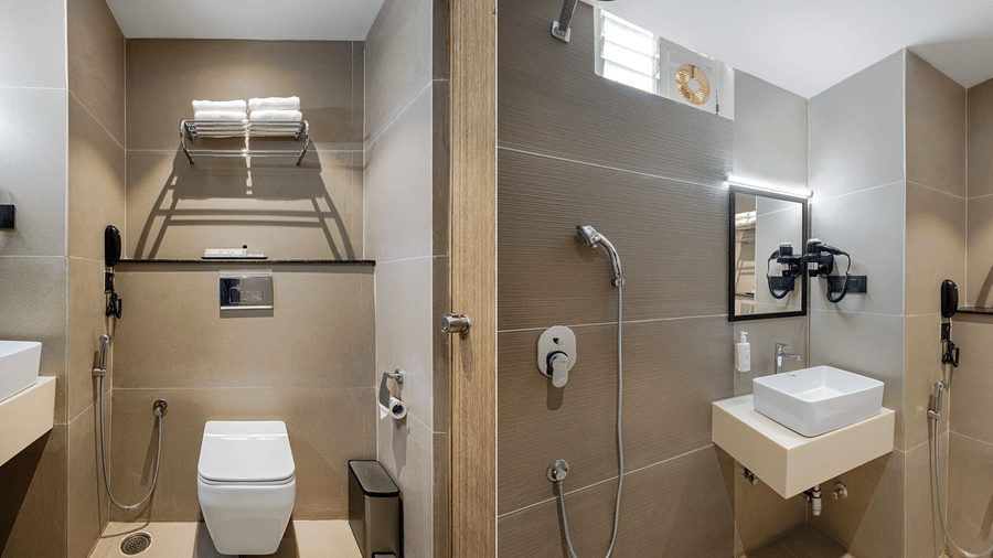 The bathroom at rooms of Monday Premium, Madhapur, featuring a handheld shower, a sink, a mirror, and a toilet seat.
