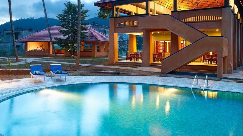 An overview of the swimming pool next to a building and loungers - Abad Green Forest, Thekkady.
