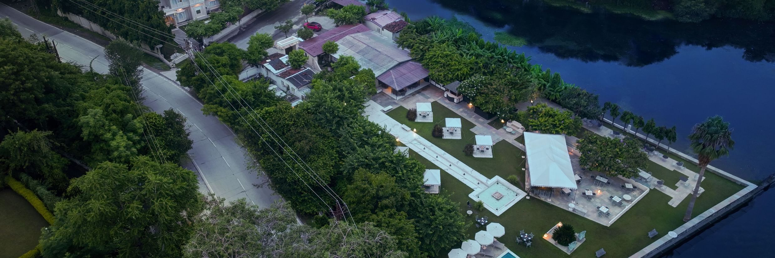 Aerial view of Ram Pratap Palace in Udaipur, India, with a modern hotel building, lush gardens, a pool, and event space by the lake.