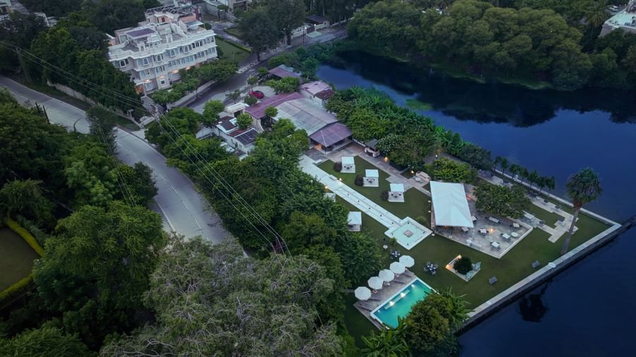 Aerial view of Ram Pratap Palace in Udaipur, India, with a modern hotel building, lush gardens, a pool, and event space by the lake.