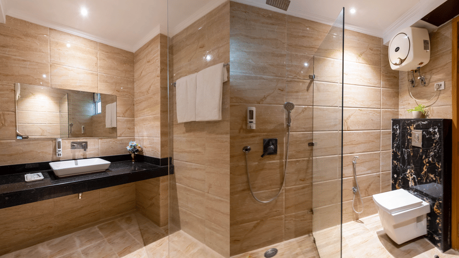 Bathroom featuring a sleek pedestal sink, a spacious glass-enclosed rain shower, and polished wall tiling at Hotel Corporate Suites