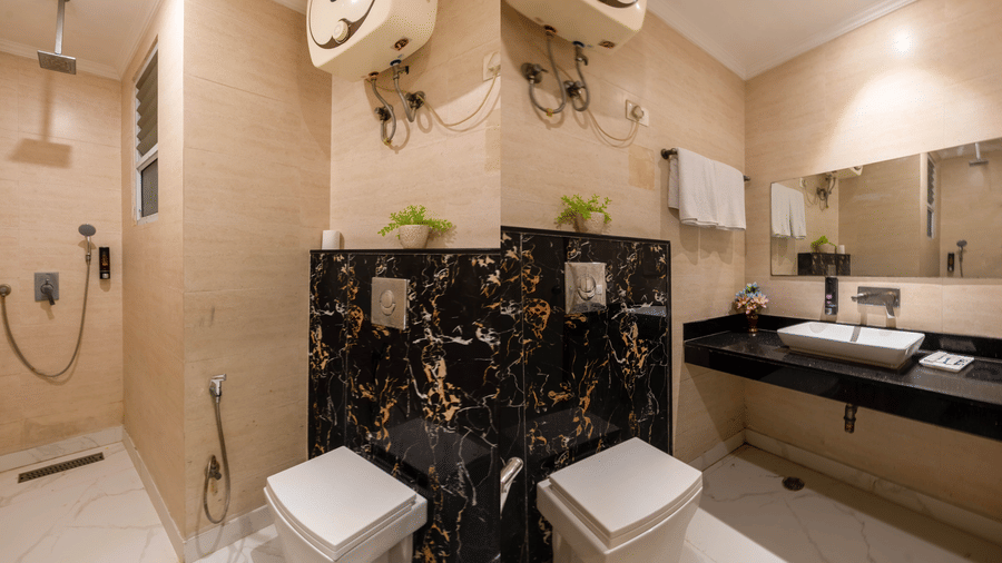 Wall tiling lines in the bathroom, showcasing a glass shower partition, a floating toilet with a dark marble background at Hotel Corporate Suites